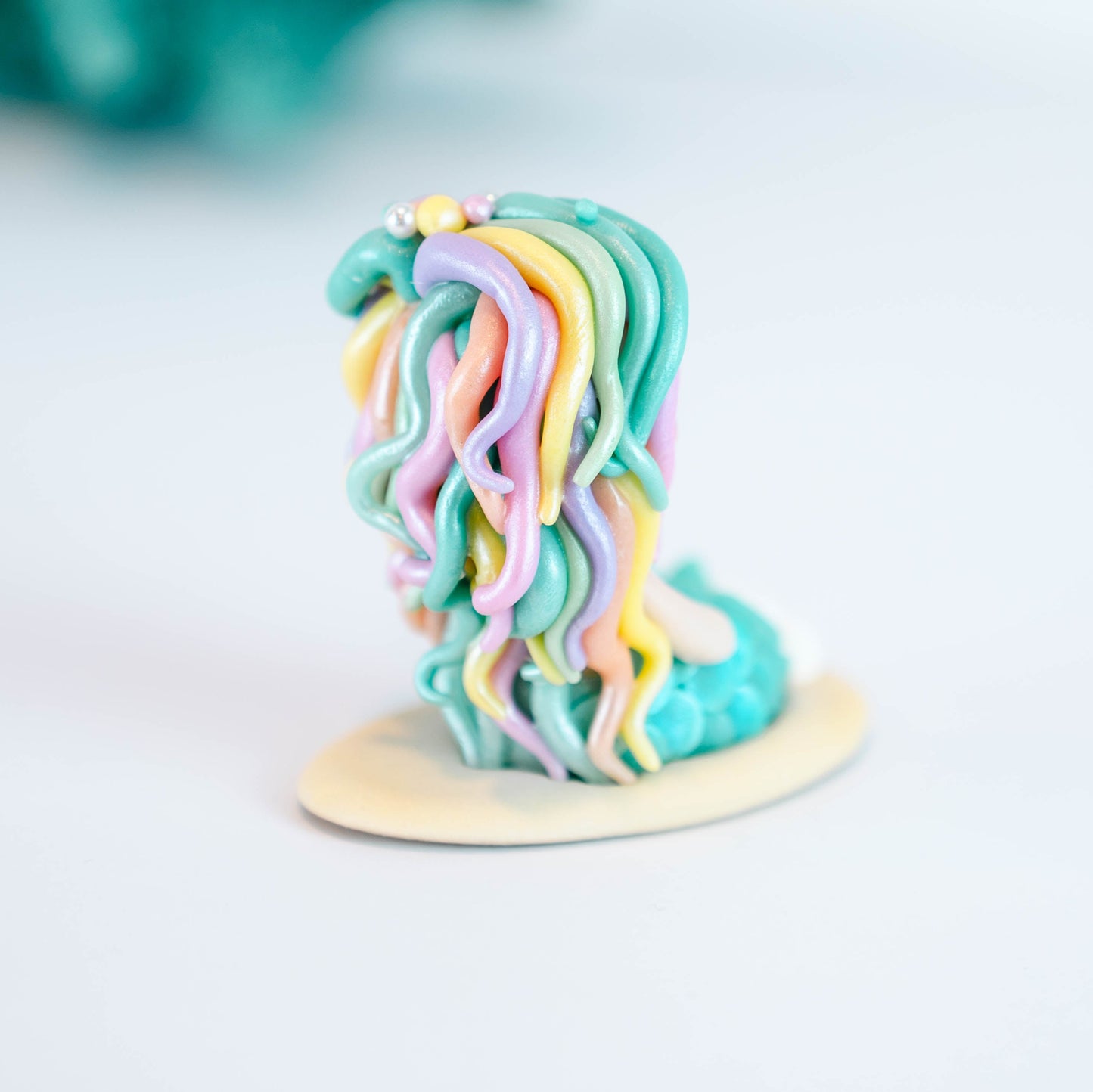 Mermaid figurine with colorful hair and tail on a light sand colored base