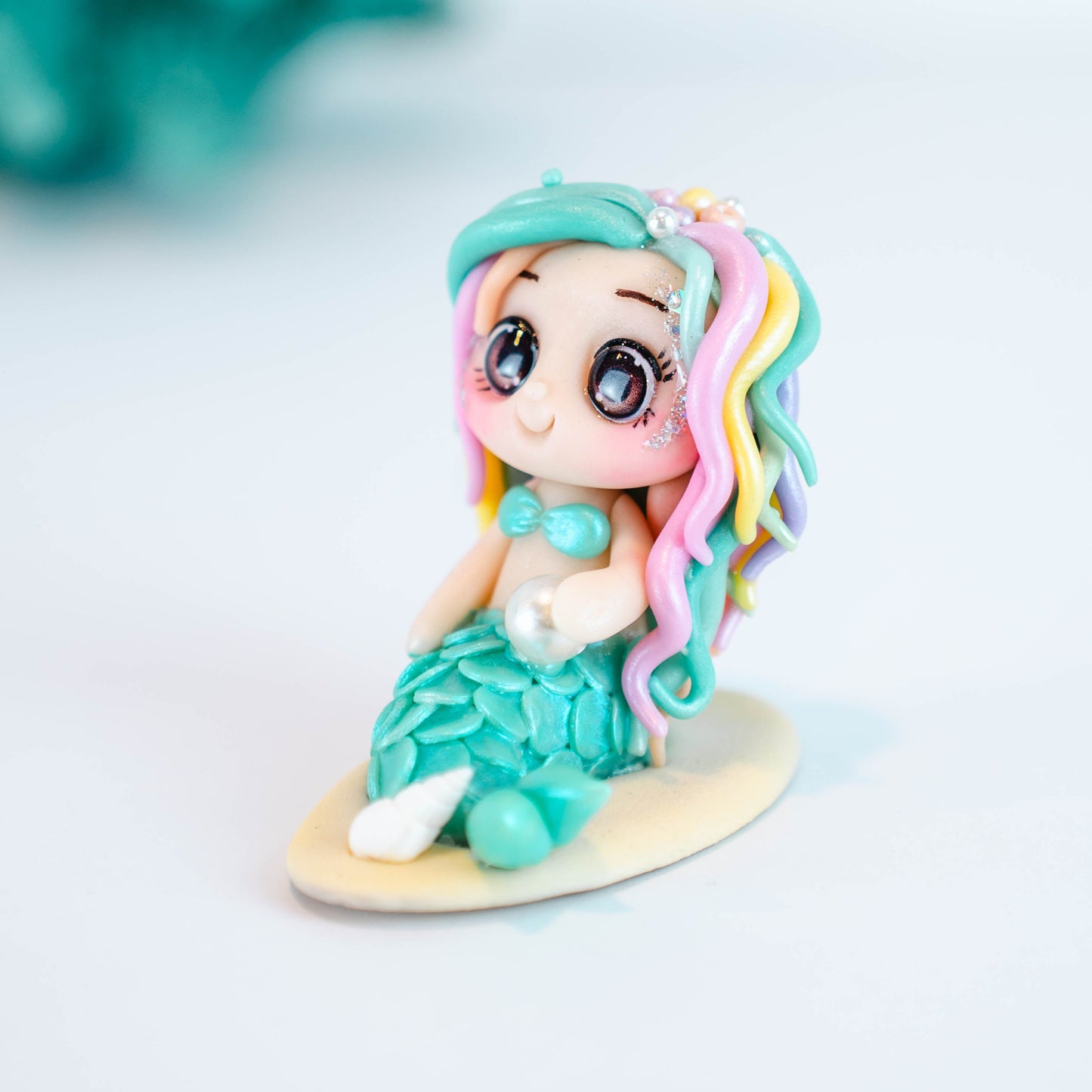 Mermaid figurine with colorful hair and tail on a light sand colored base