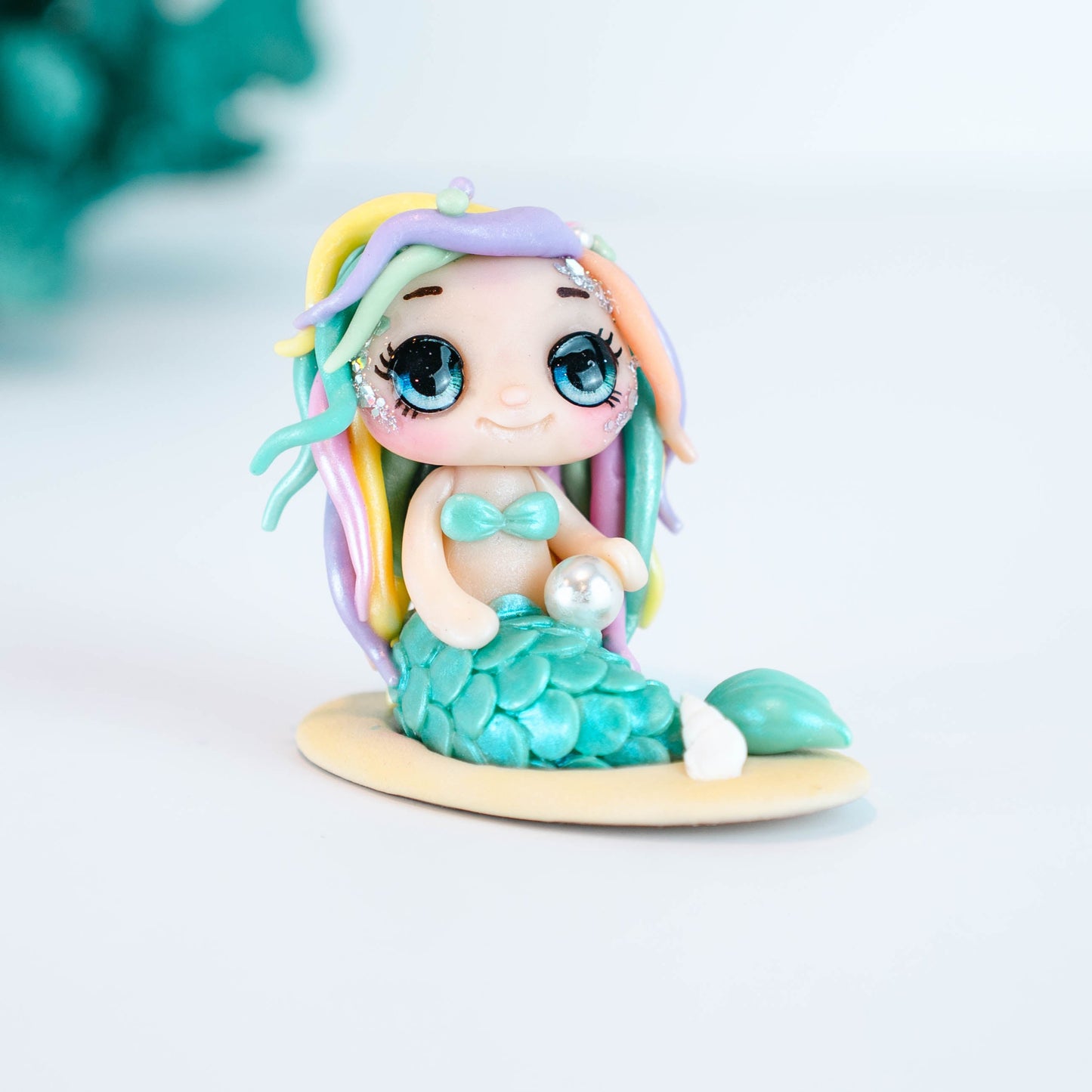 Mermaid figurine with colorful hair and tail on a light sand colored base