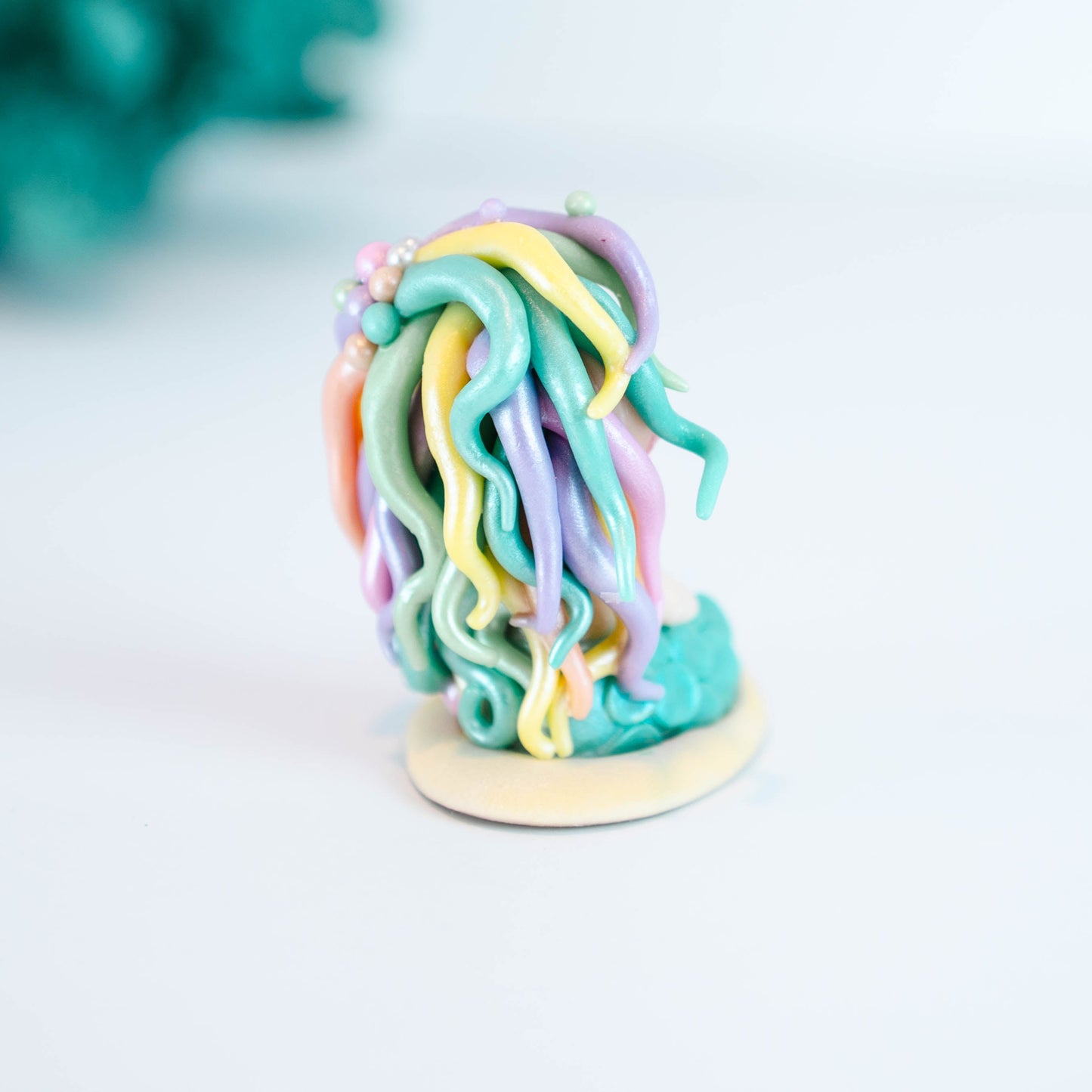 Mermaid figurine with colorful hair and tail on a light sand colored base