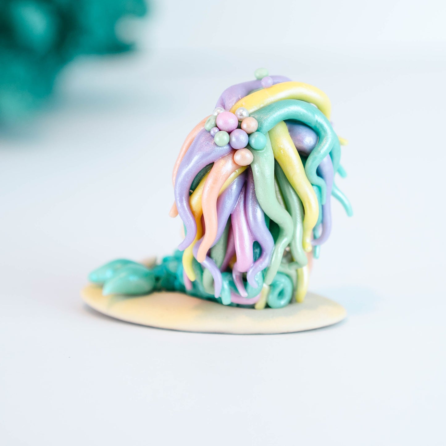 Mermaid figurine with colorful hair and tail on a light sand colored base