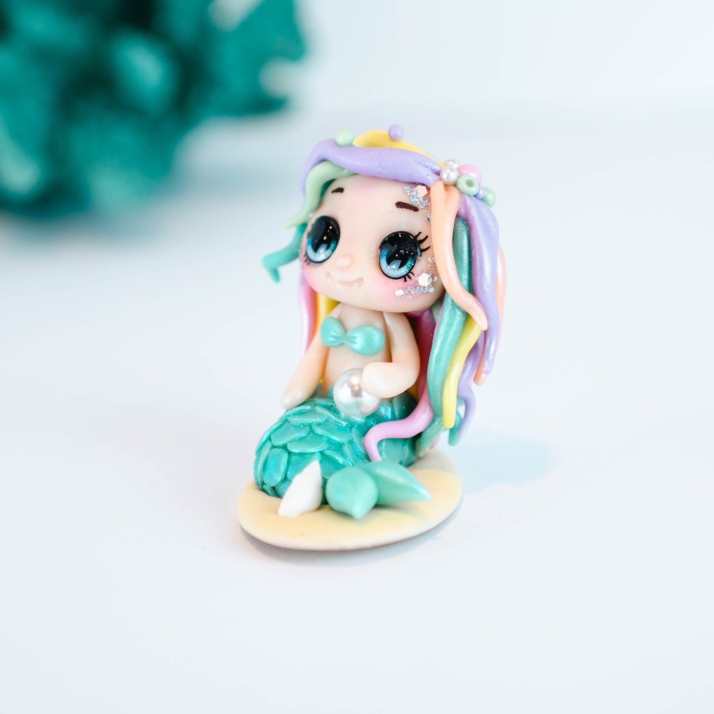 Mermaid figurine with colorful hair and tail on a light sand colored base