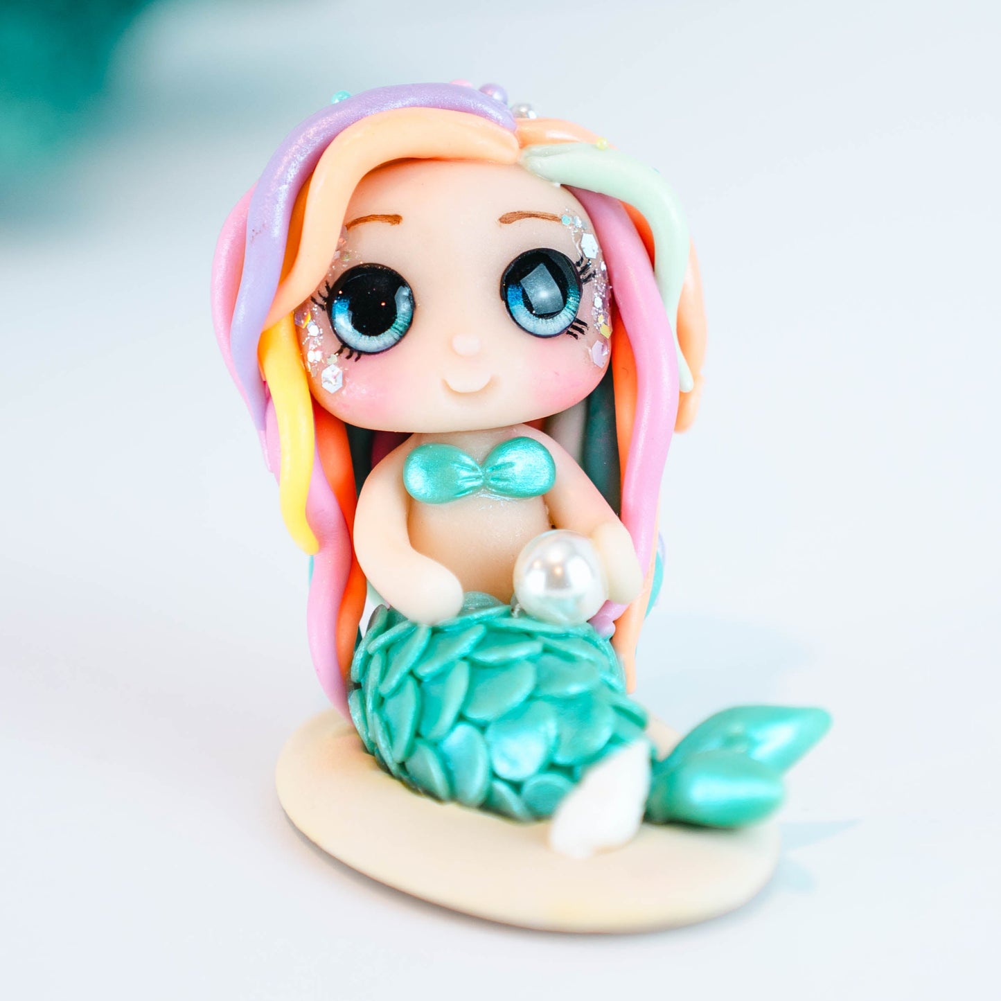Mermaid figurine with colorful hair and tail on a light sand colored base