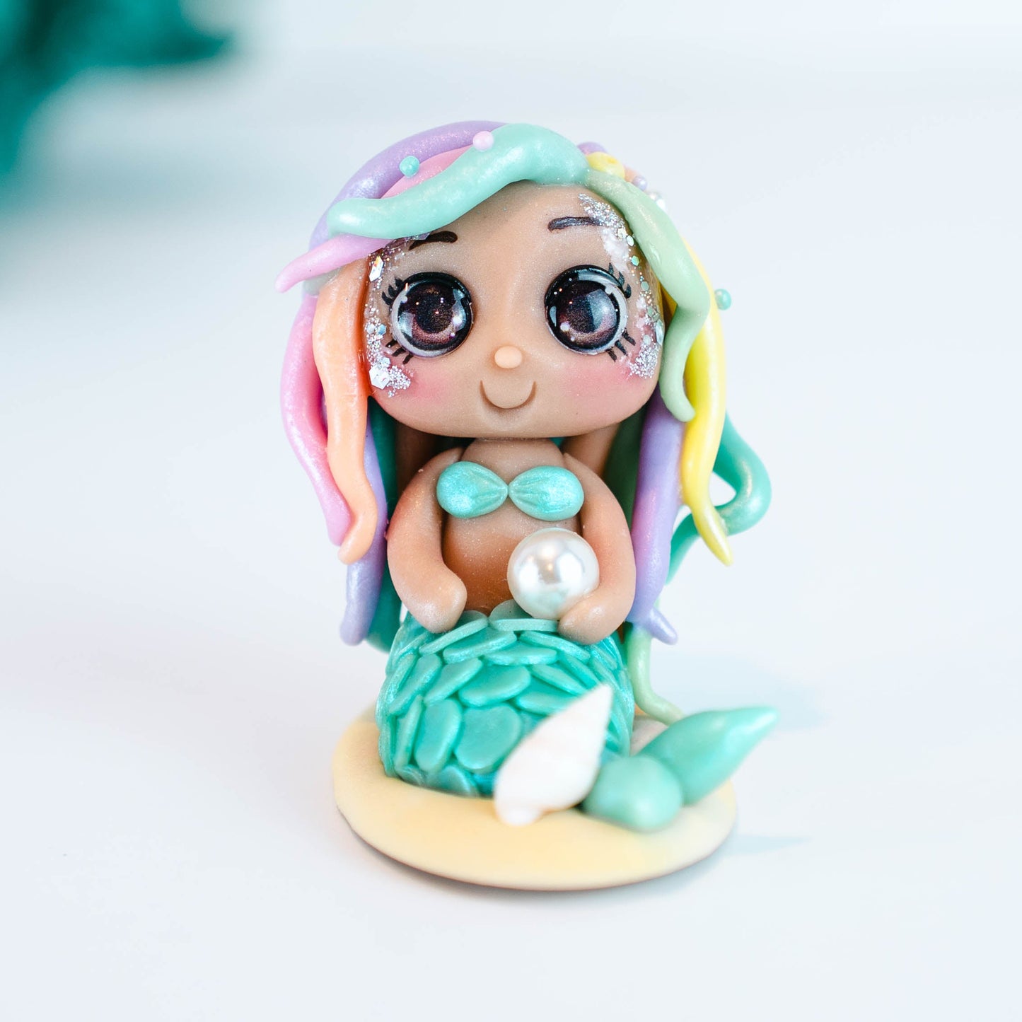 Mermaid figurine with colorful hair and tail on a light sand colored base
