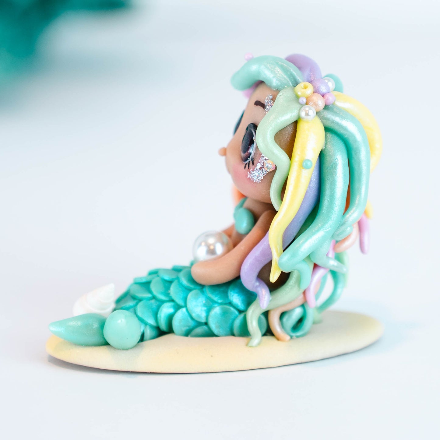Mermaid figurine with colorful hair and tail on a light sand colored base