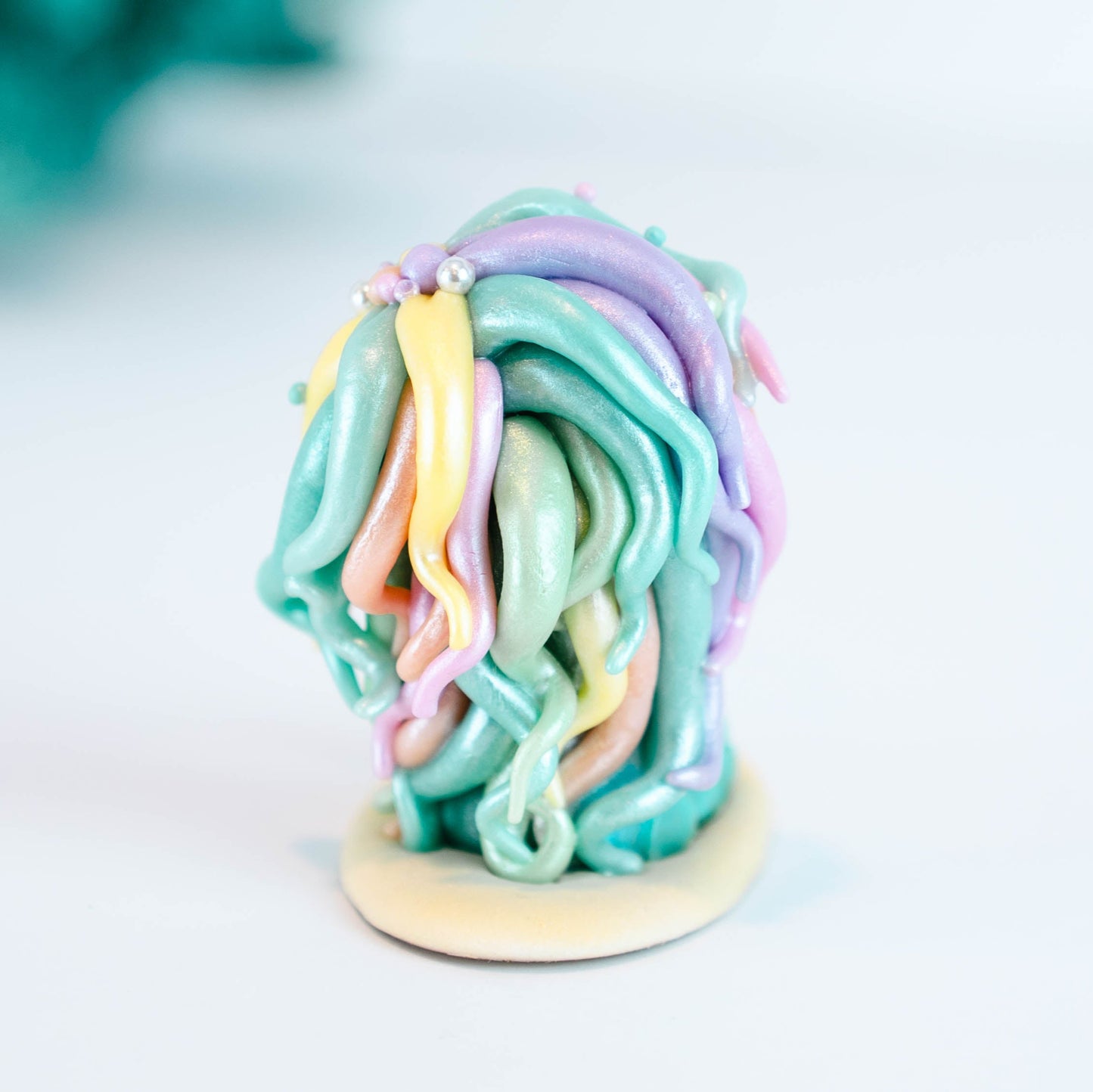 Mermaid figurine with colorful hair and tail on a light sand colored base