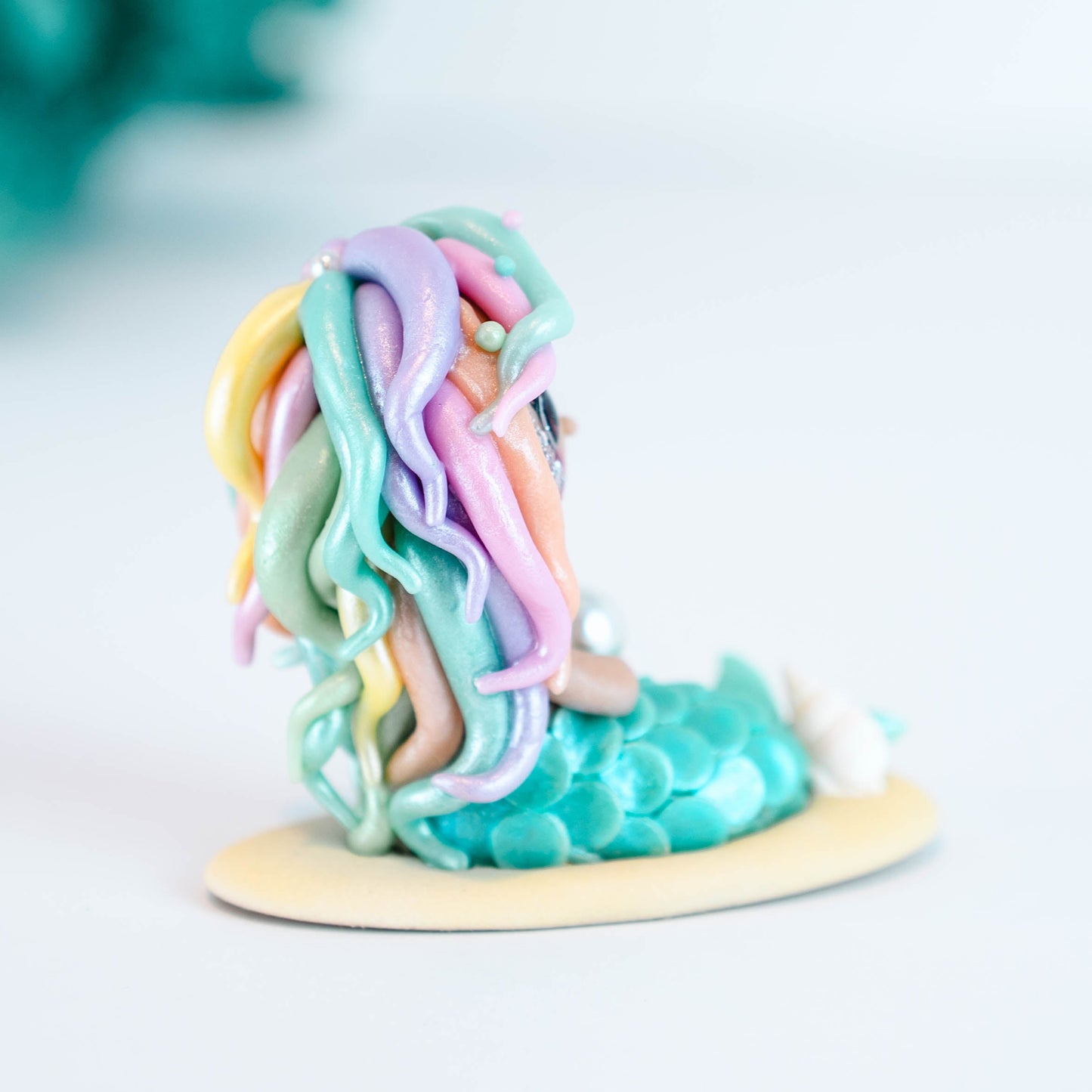 Mermaid figurine with colorful hair and tail on a light sand colored base