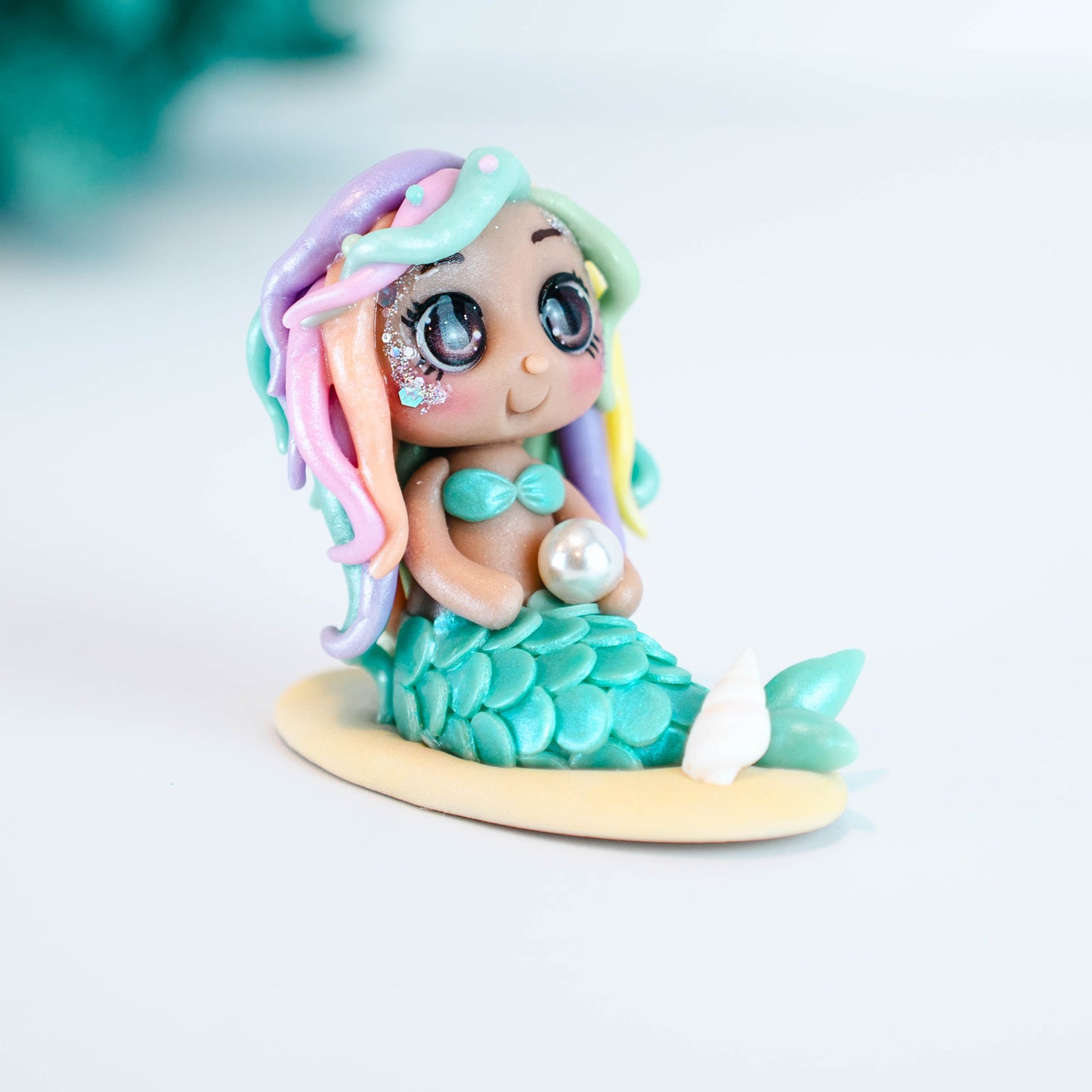 Mermaid figurine with colorful hair and tail on a light sand colored base