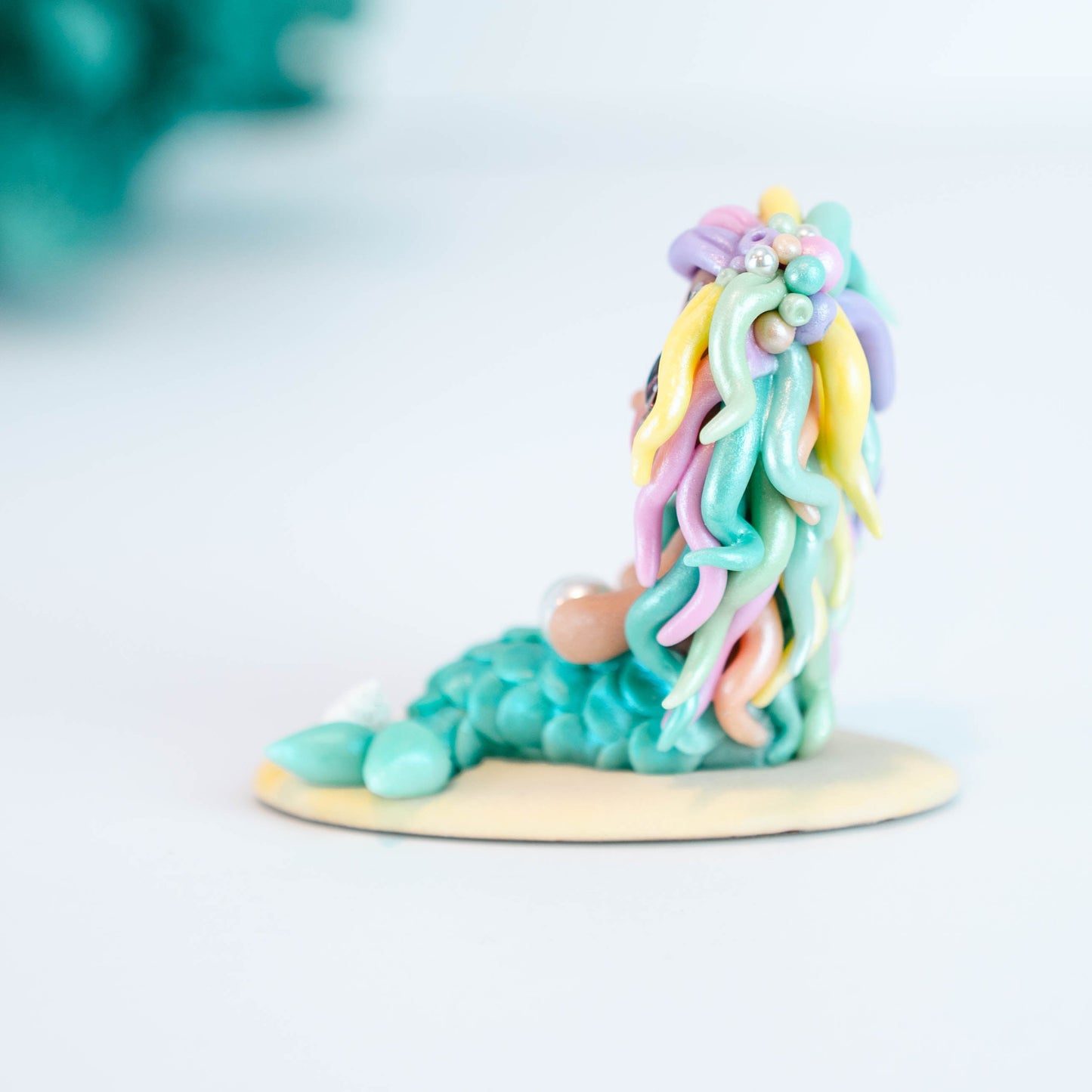 Mermaid figurine with colorful hair and tail on a light sand colored base