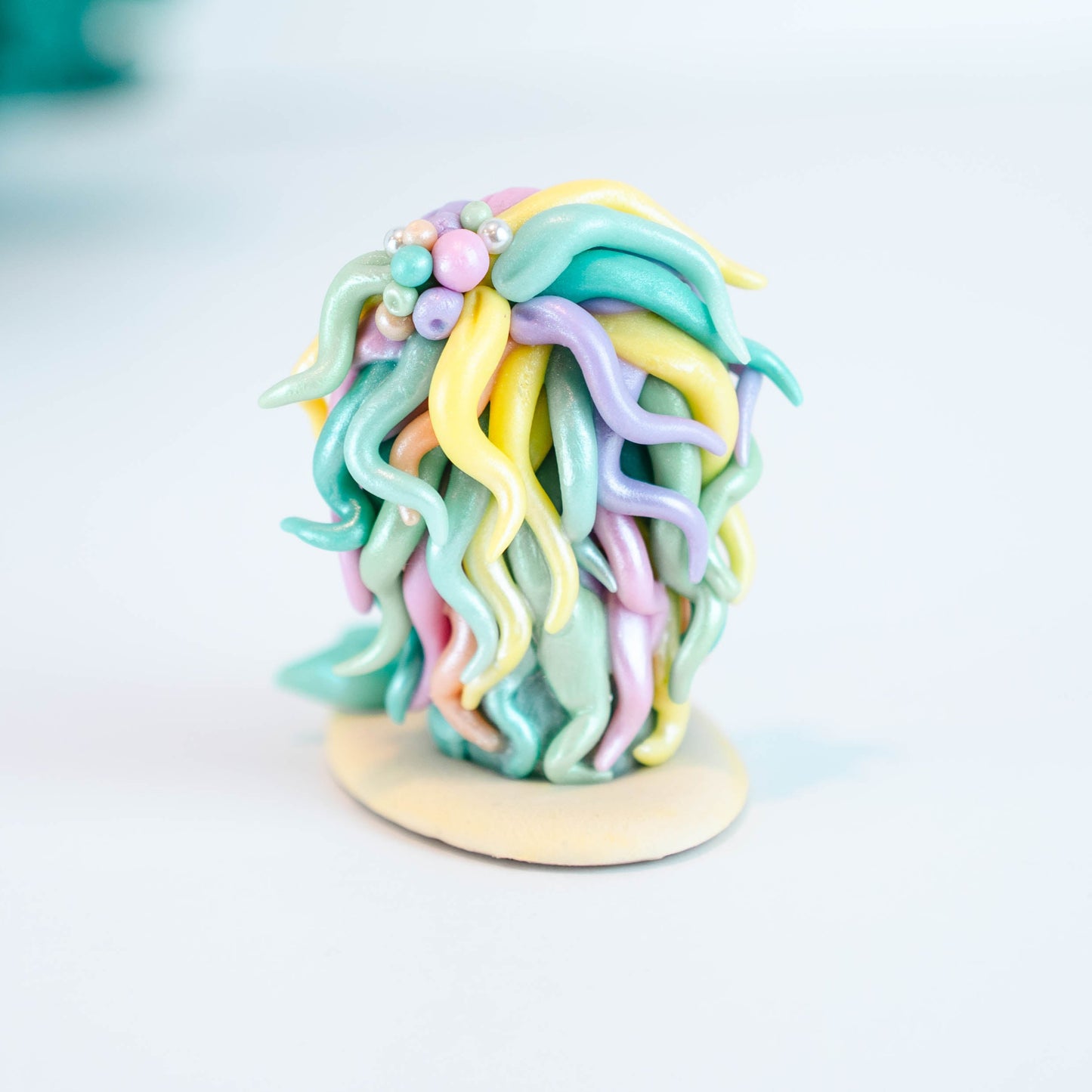 Mermaid figurine with colorful hair and tail on a light sand colored base