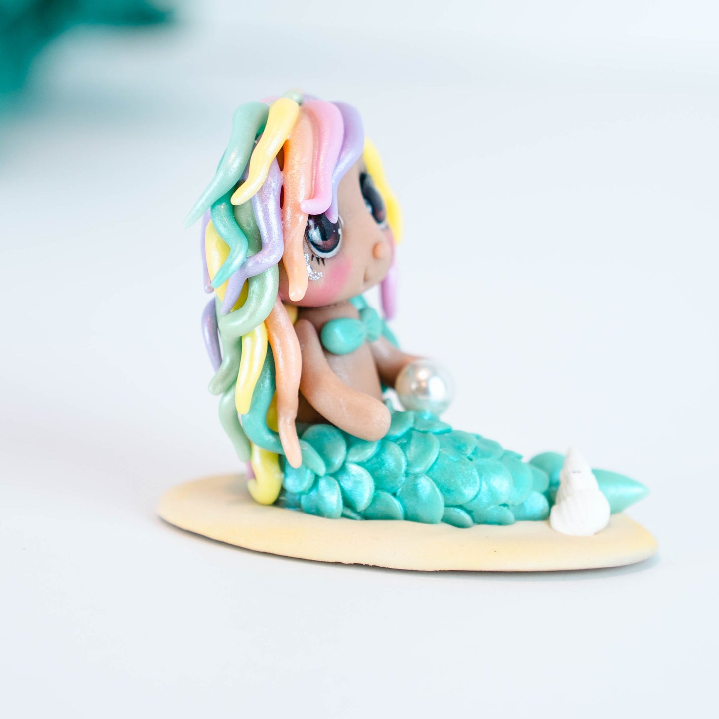 Mermaid figurine with colorful hair and tail on a light sand colored base