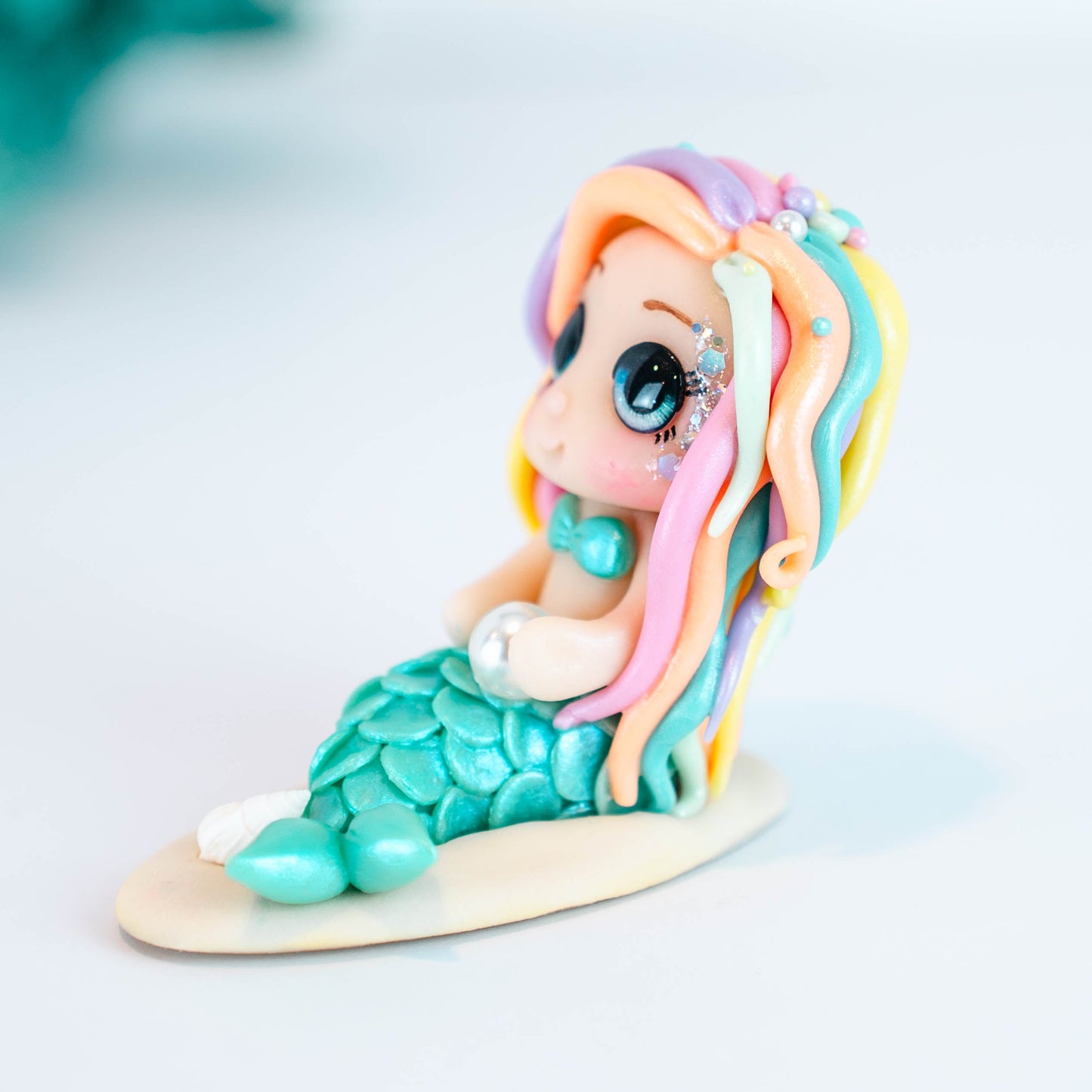 Mermaid figurine with colorful hair and tail on a light sand colored base