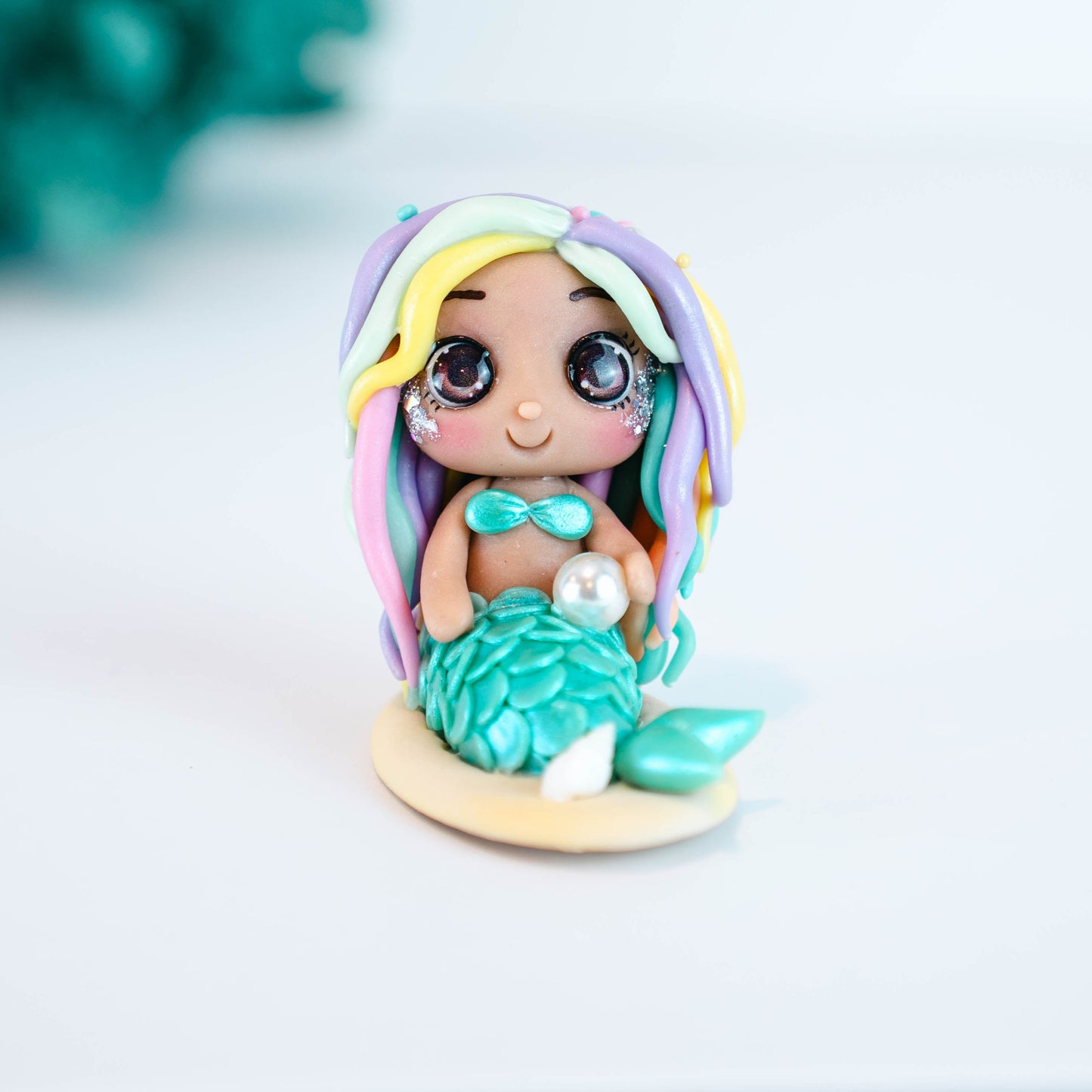 Mermaid figurine with colorful hair and tail on a light sand colored base