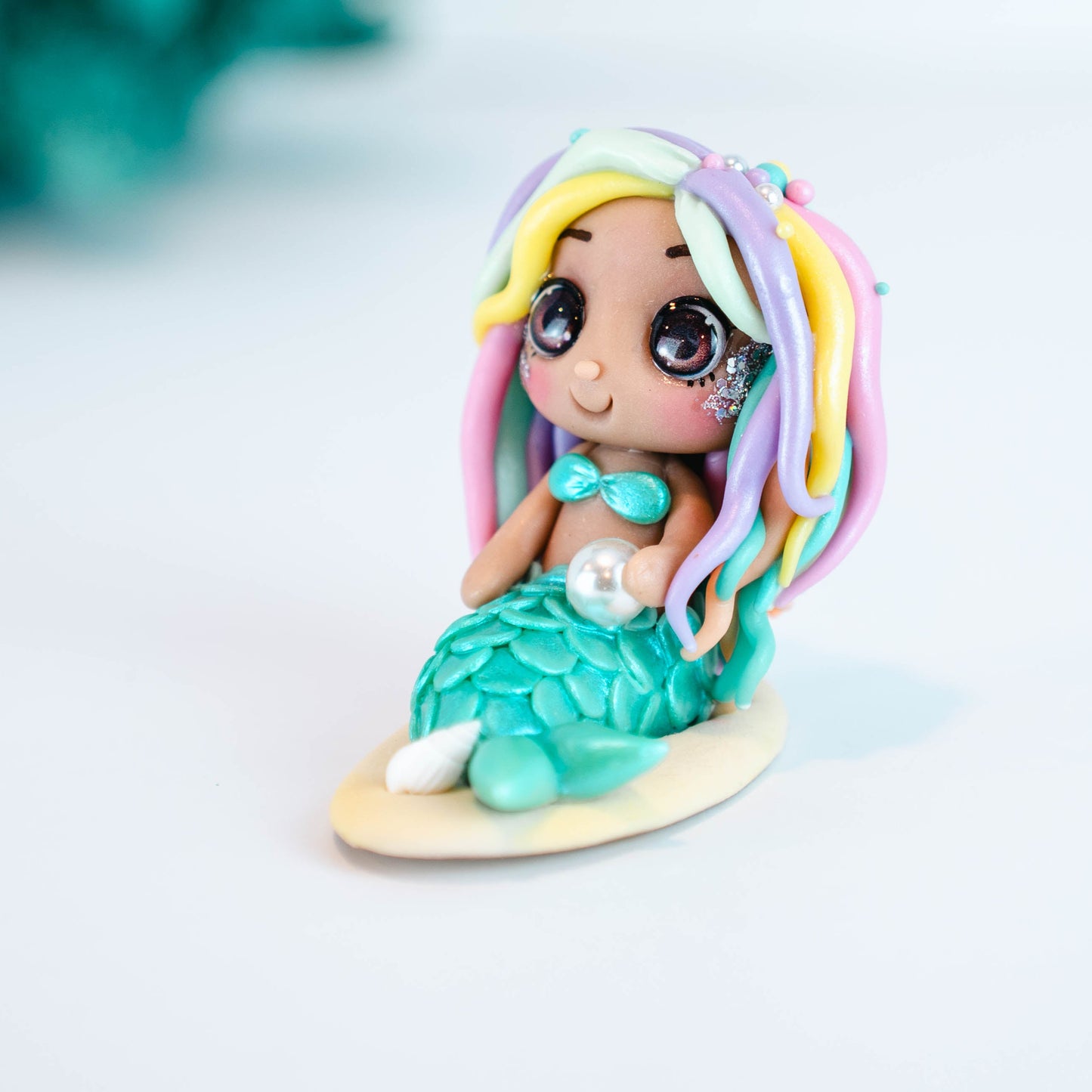 Mermaid figurine with colorful hair and tail on a light sand colored base