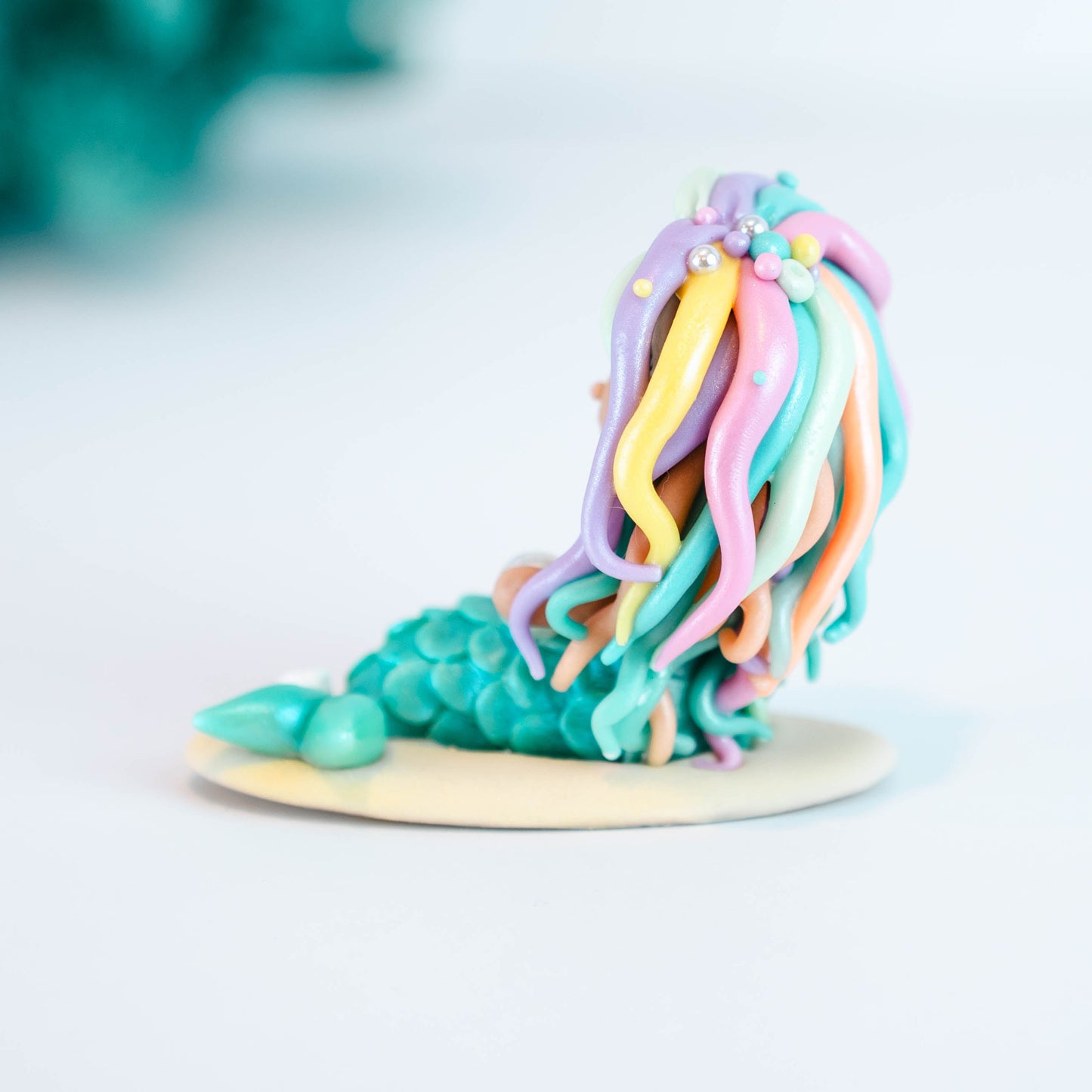 Mermaid figurine with colorful hair and tail on a light sand colored base