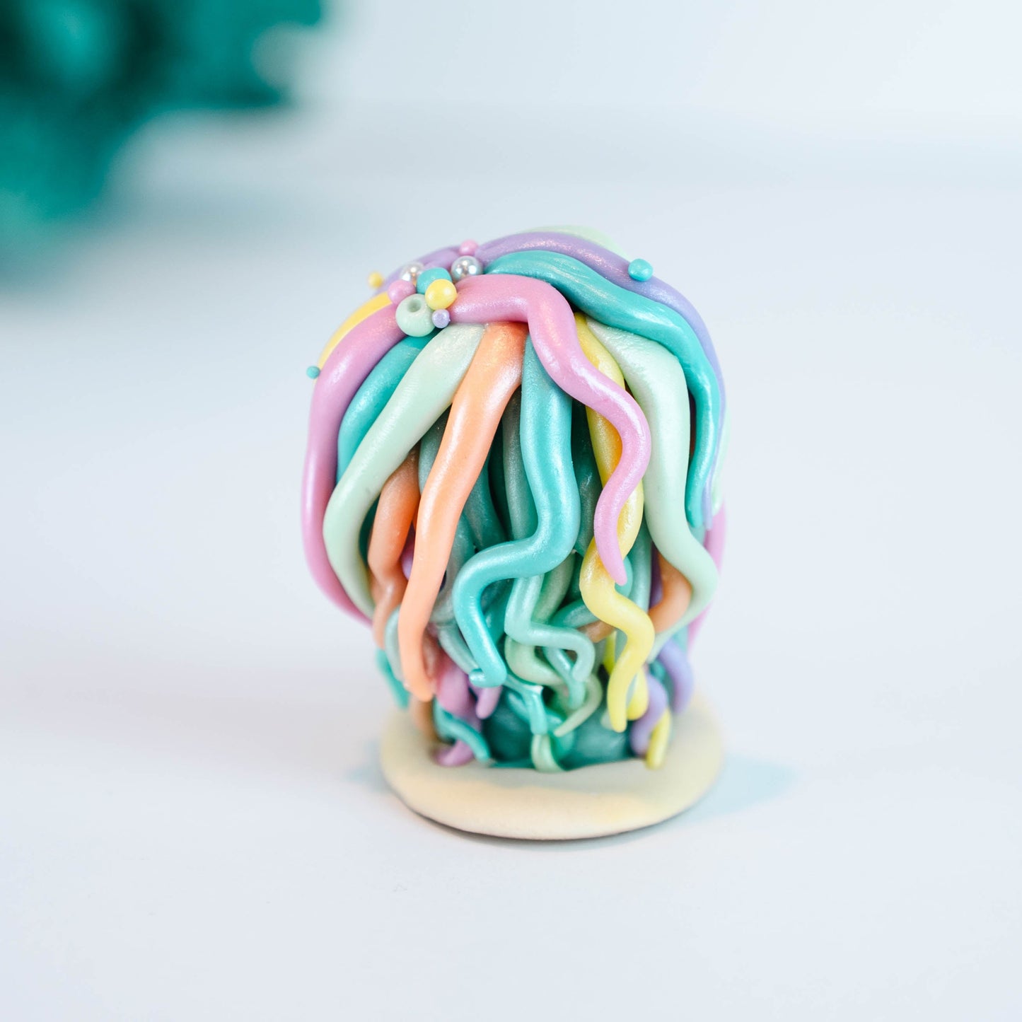 Mermaid figurine with colorful hair and tail on a light sand colored base