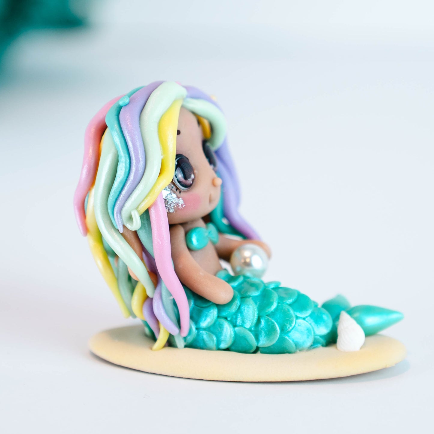 Mermaid figurine with colorful hair and tail on a light sand colored base