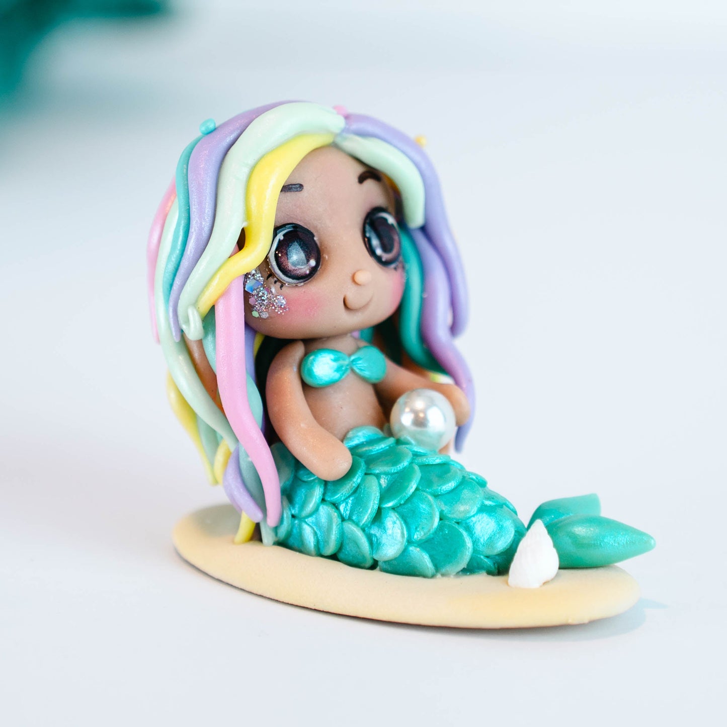 Mermaid figurine with colorful hair and tail on a light sand colored base