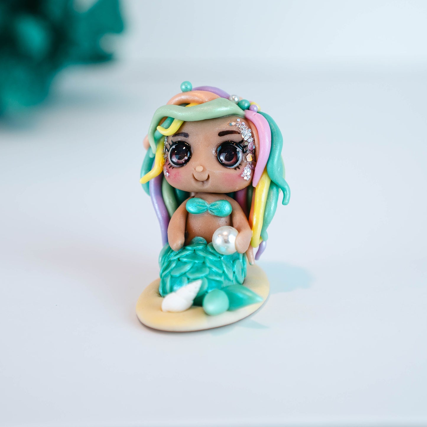 Mermaid figurine with colorful hair and tail on a light sand colored base