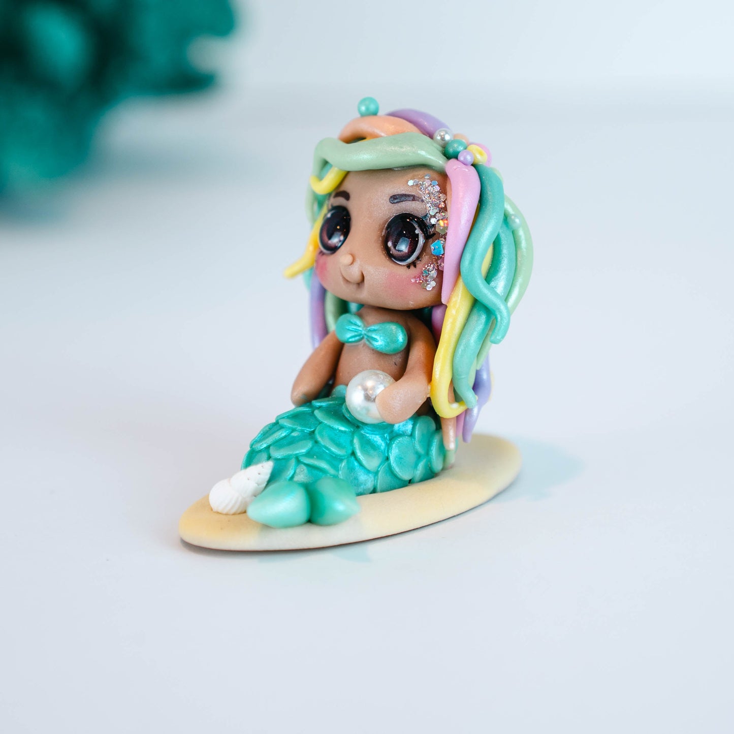 Mermaid figurine with colorful hair and tail on a light sand colored base