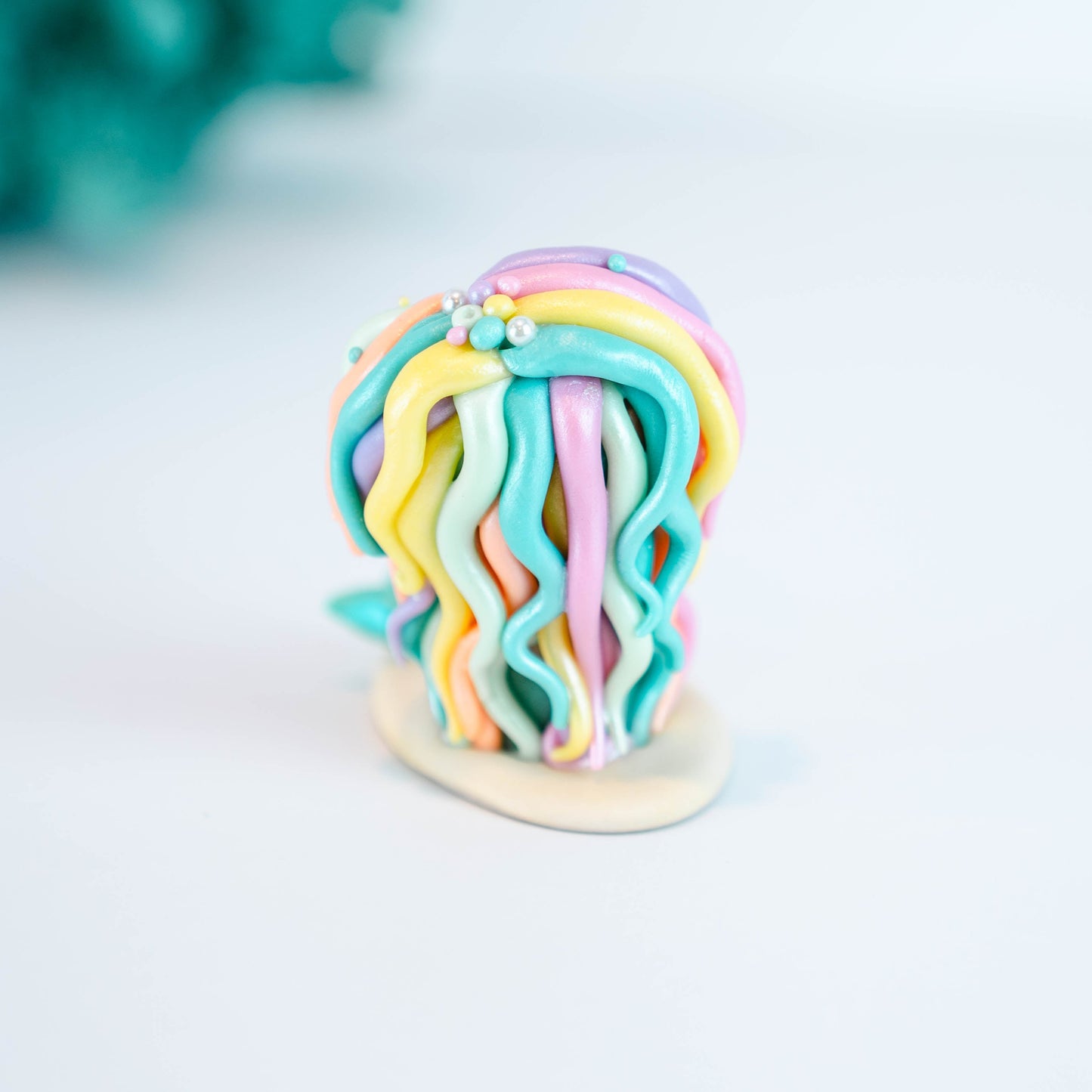 Mermaid figurine with colorful hair and tail on a light sand colored base