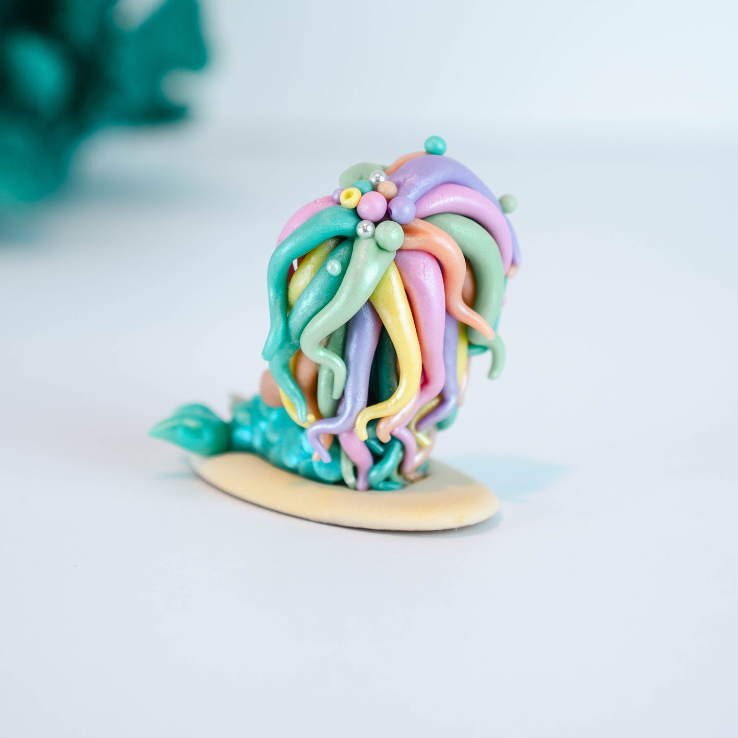 Mermaid figurine with colorful hair and tail on a light sand colored base