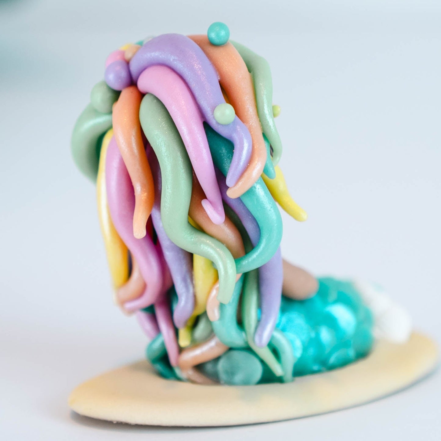 Mermaid figurine with colorful hair and tail on a light sand colored base