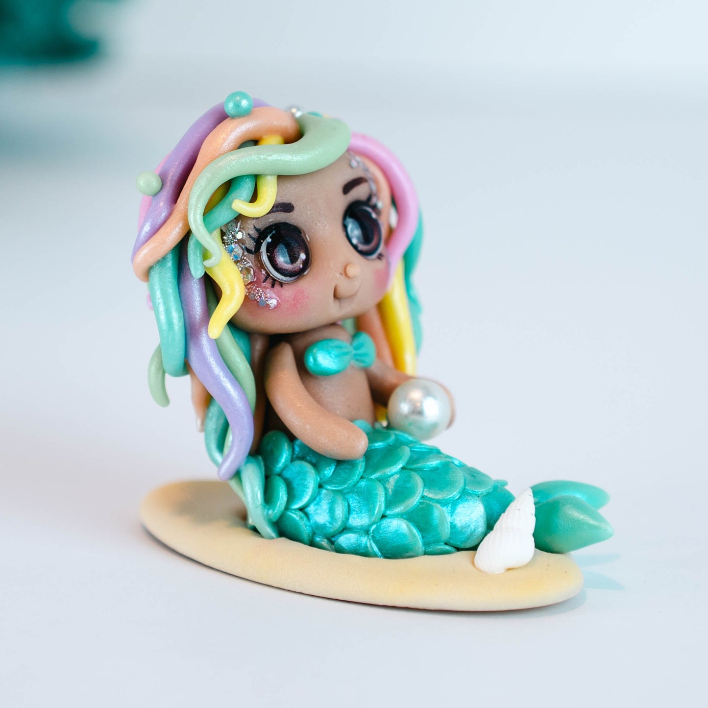 Mermaid figurine with colorful hair and tail on a light sand colored base