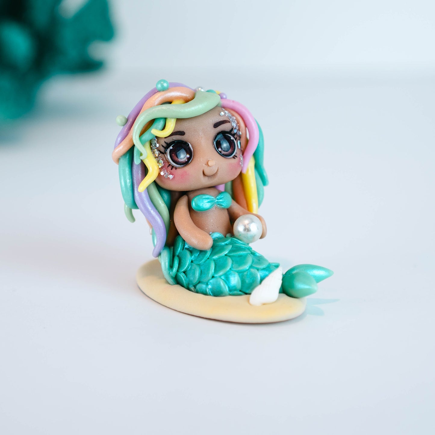 Mermaid figurine with colorful hair and tail on a light sand colored base
