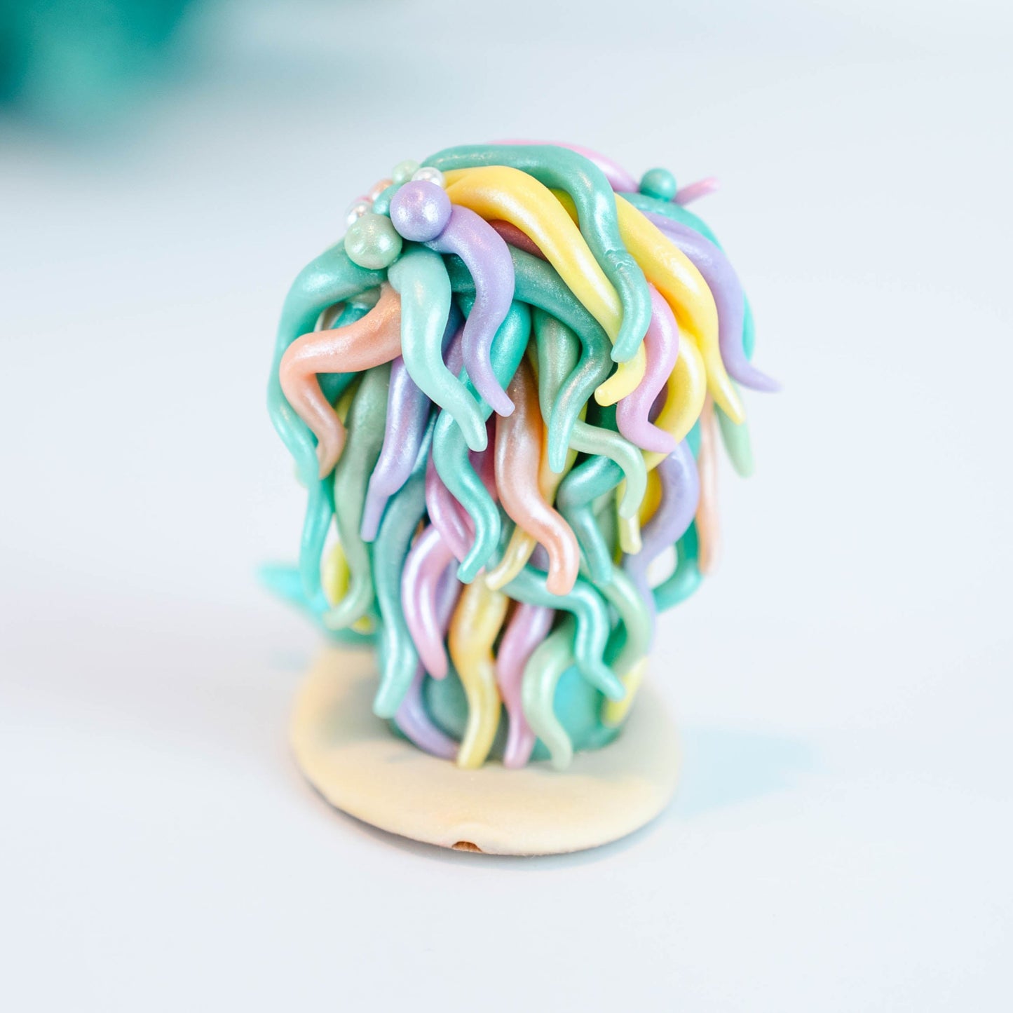 Mermaid figurine with colorful hair and tail on a light sand colored base