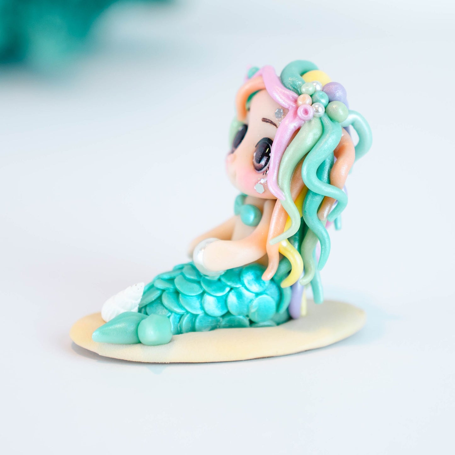Mermaid figurine with colorful hair and tail on a light sand colored base