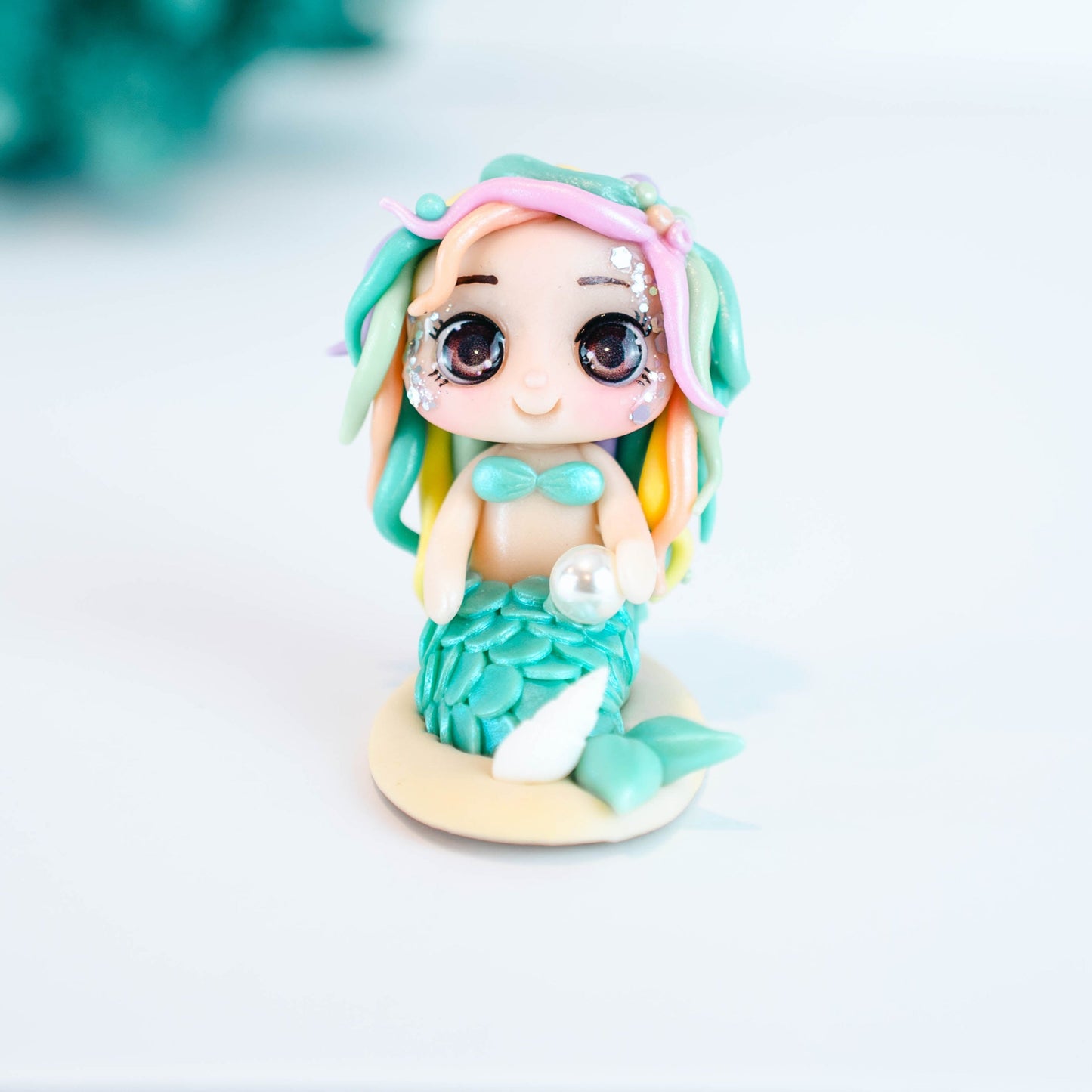 Mermaid figurine with colorful hair and tail on a light sand colored base