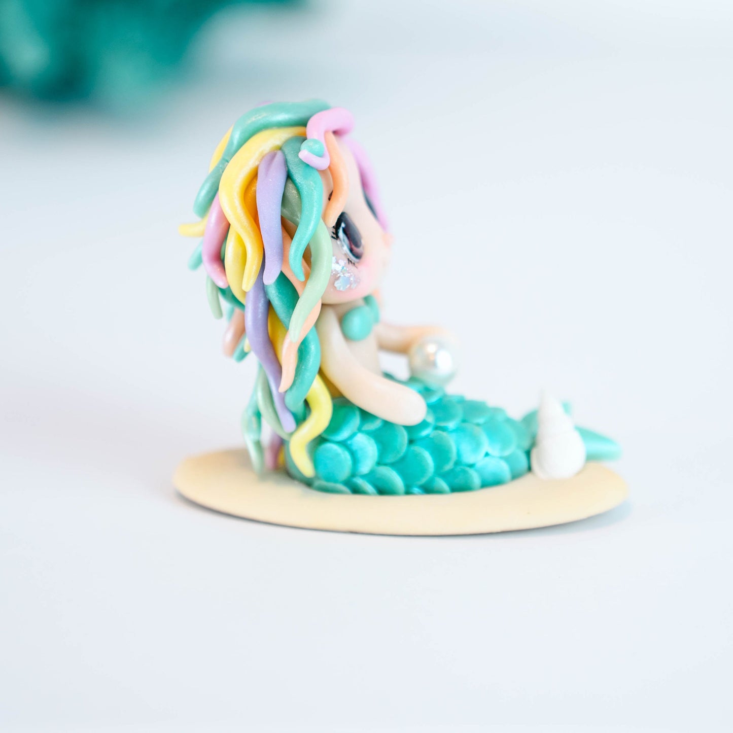 Mermaid figurine with colorful hair and tail on a light sand colored base