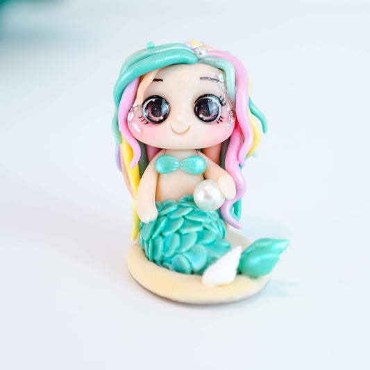 Mermaid figurine with colorful hair and tail on a light sand colored base
