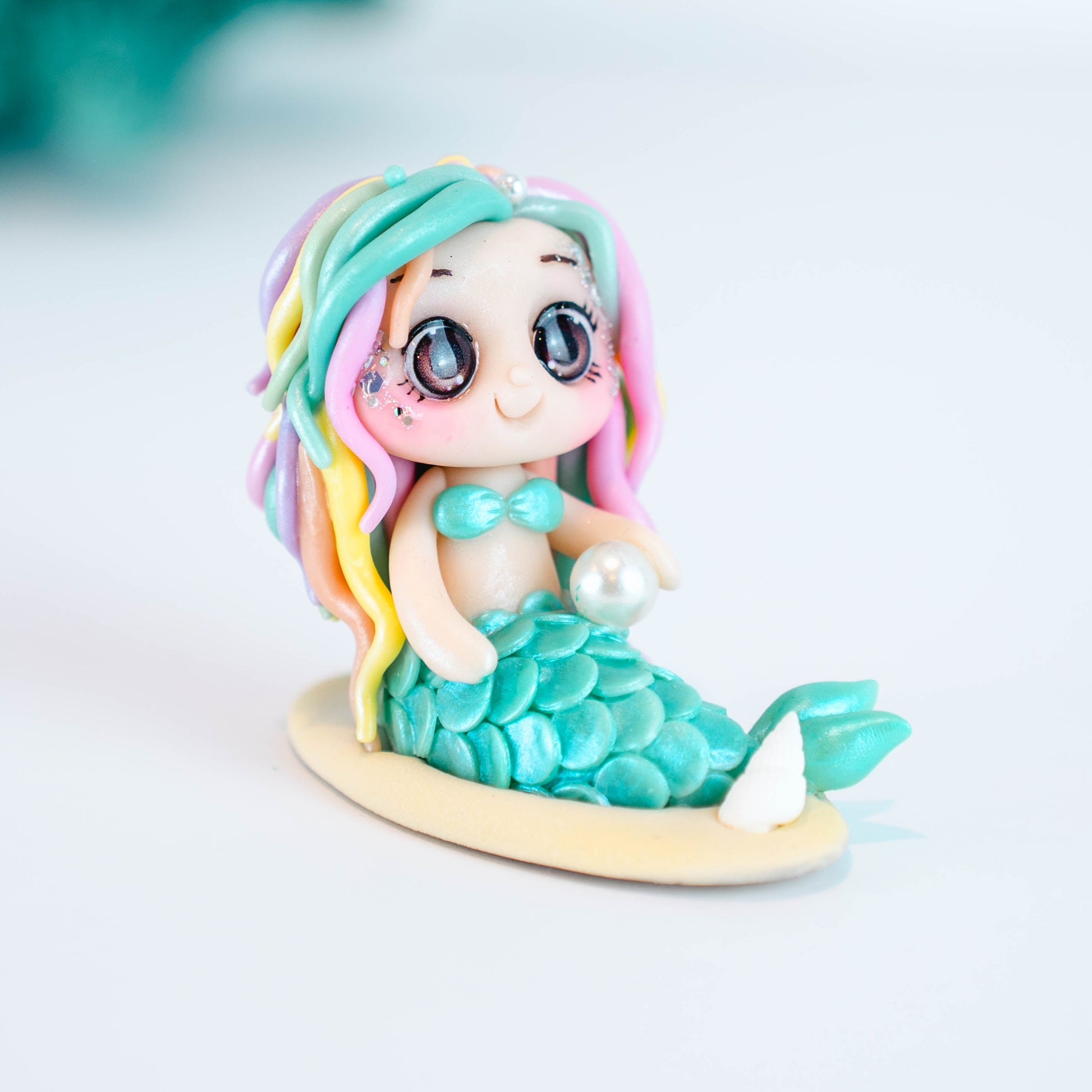 Mermaid figurine with colorful hair and tail on a light sand colored base
