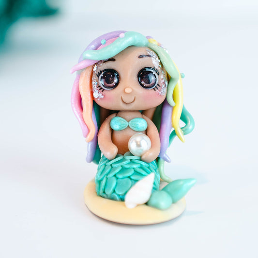 Mermaid figurine with colorful hair and tail on a light sand colored base