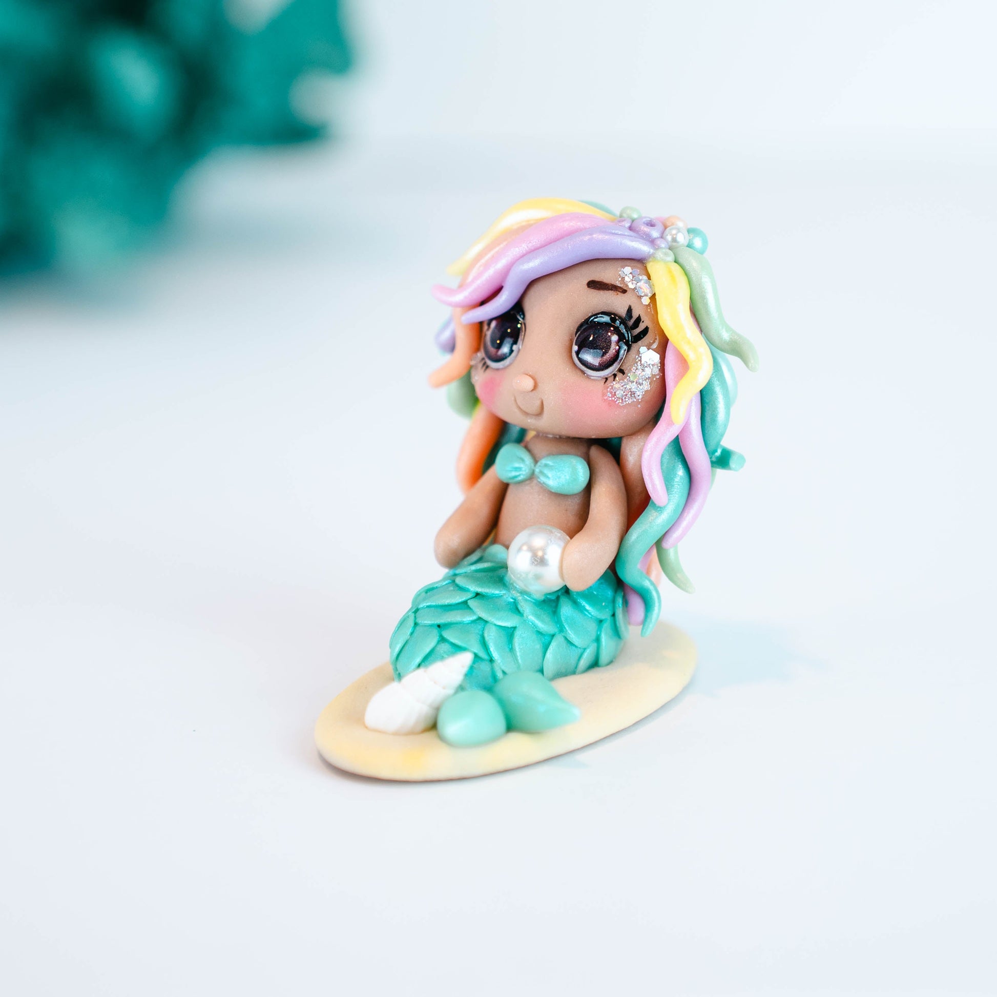Mermaid figurine with colorful hair and tail on a light sand colored base