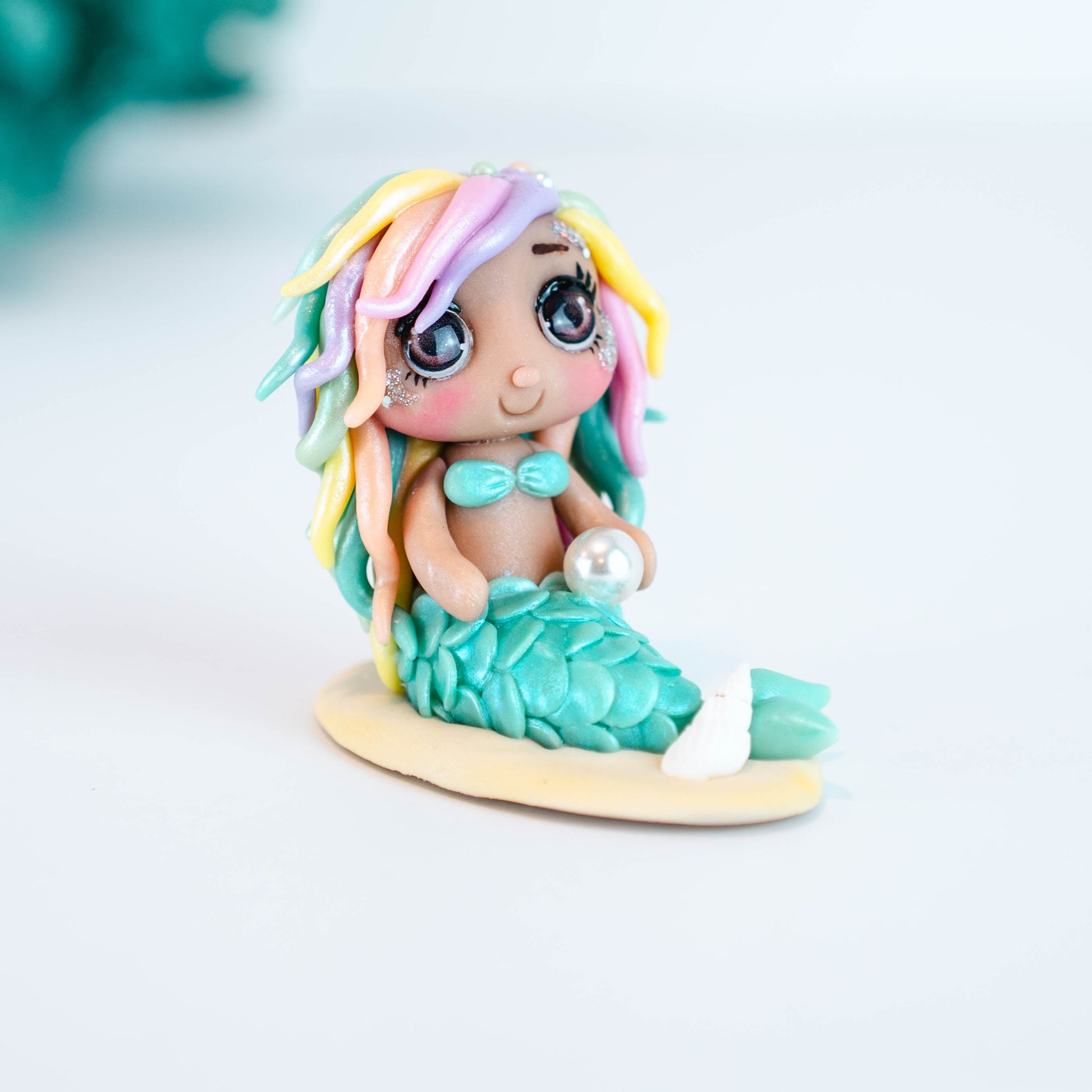 Mermaid figurine with colorful hair and tail on a light sand colored base