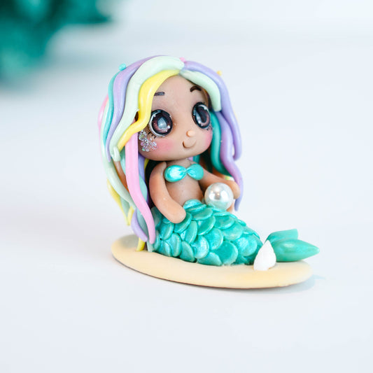 Mermaid figurine with colorful hair and tail on a light sand colored base