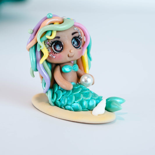 Mermaid figurine with colorful hair and tail on a light sand colored base
