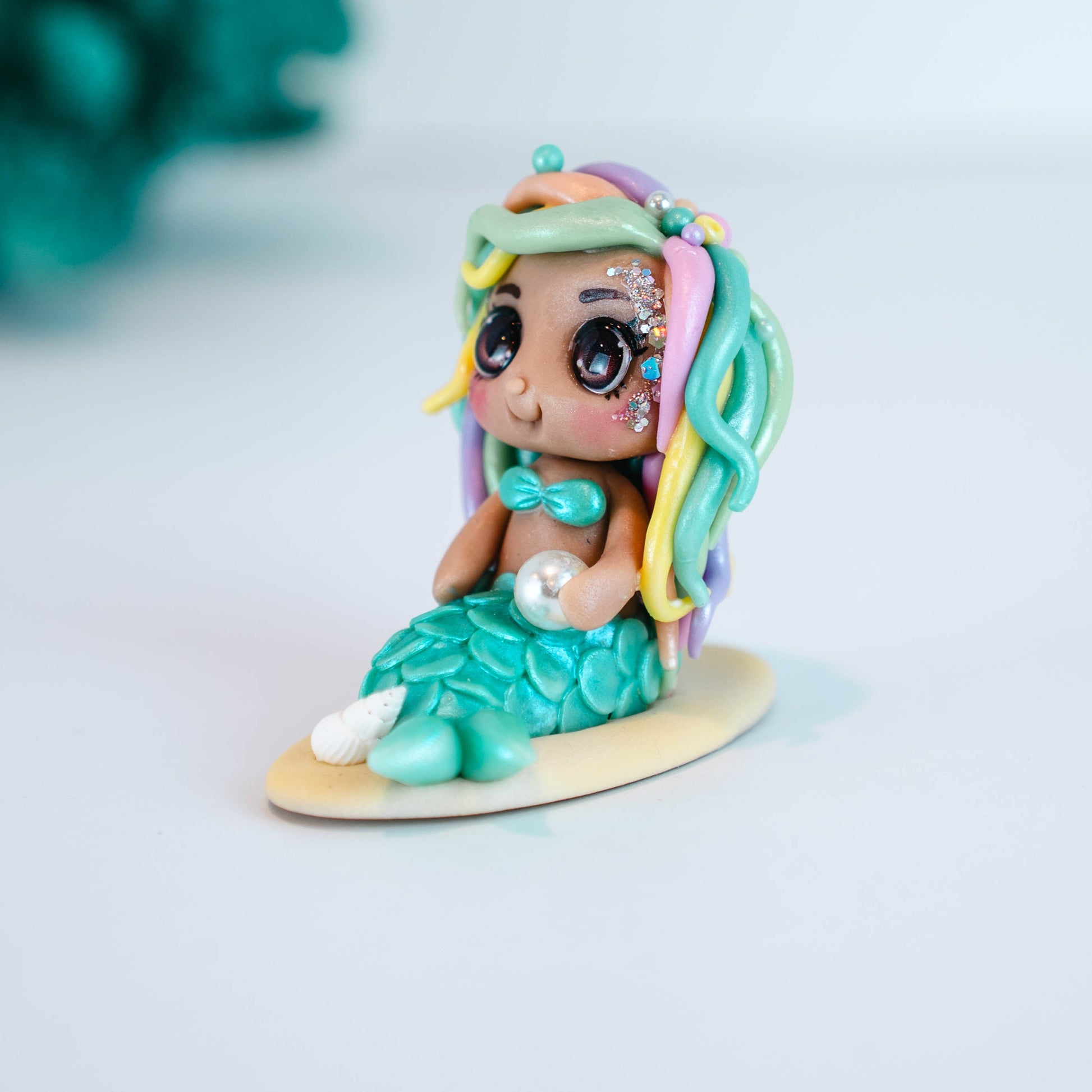 Mermaid figurine with colorful hair and tail on a light sand colored base