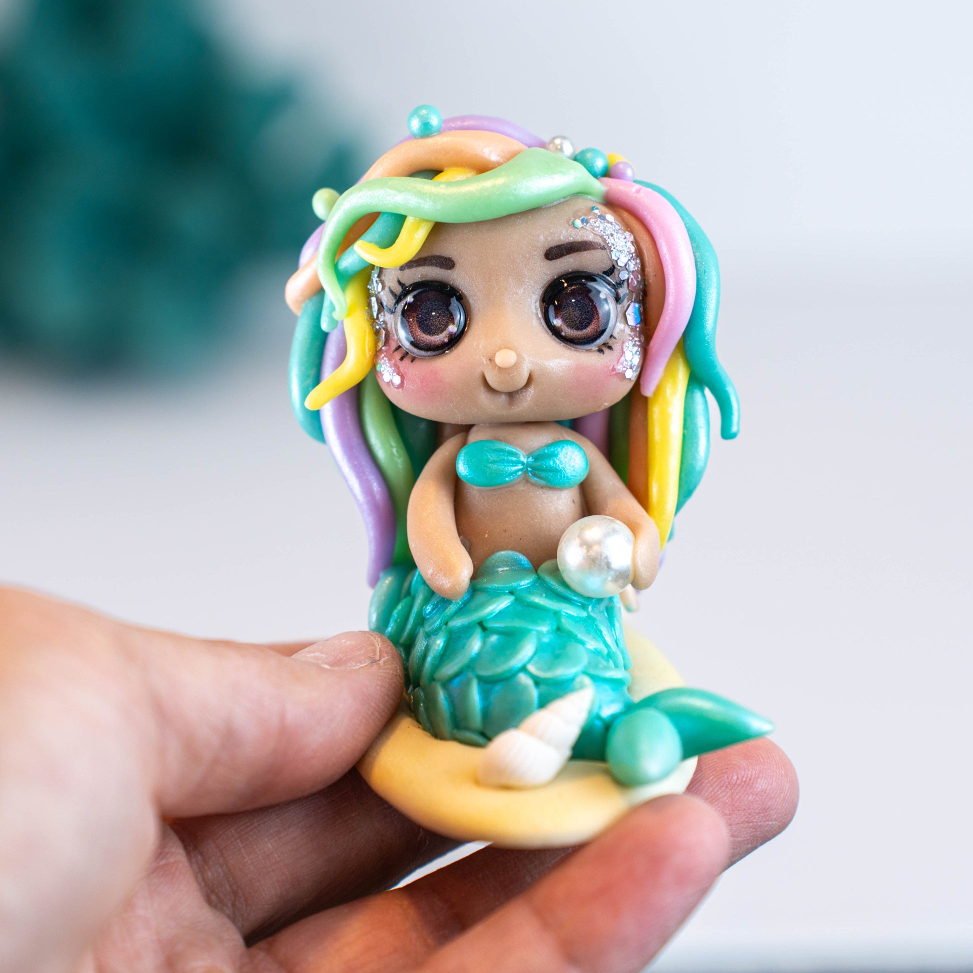 Mermaid figurine with colorful hair and tail on a light sand colored base