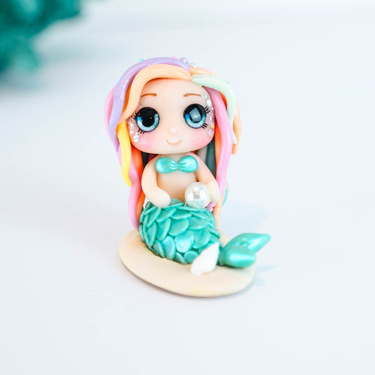 Mermaid figurine with colorful hair and tail on a light sand colored base