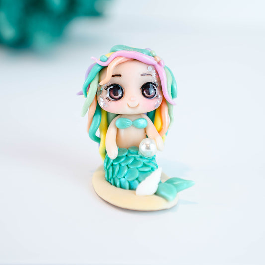 Mermaid figurine with colorful hair and tail on a light sand colored base